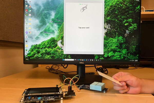 Computer screen with hand tapping a card on a terminal
